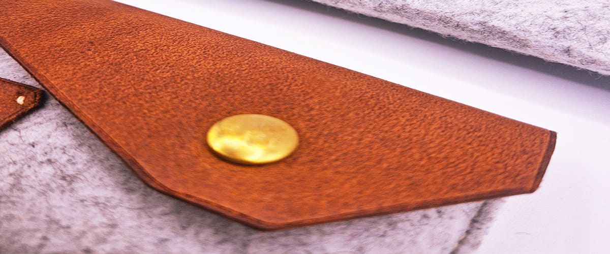 détail rabat pochette bi matière cuir camel et feutre. bouton pression laiton doré